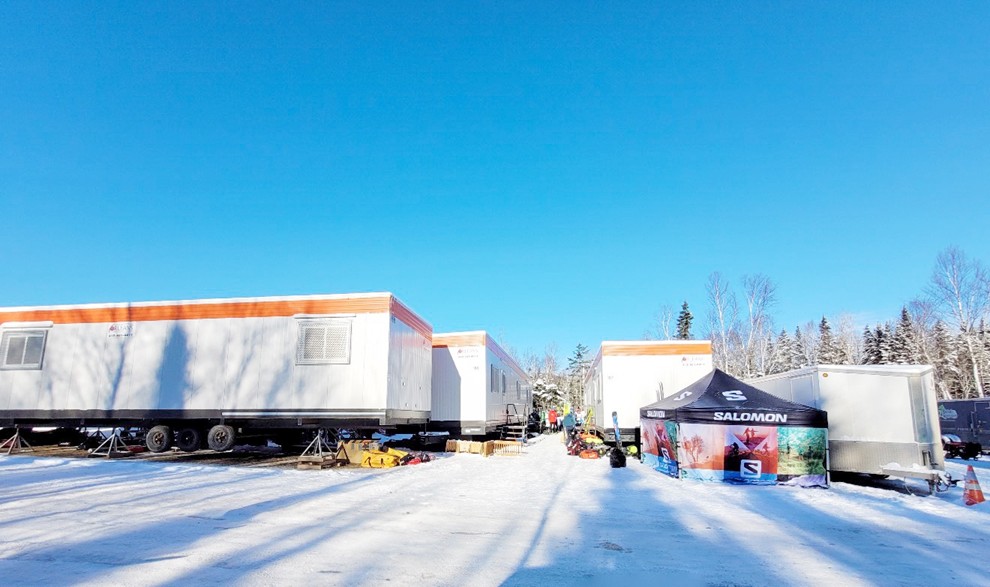 Roulottes de chantier installées sur un site enneigé avec tente événementielle et équipements pour un événement hivernal.